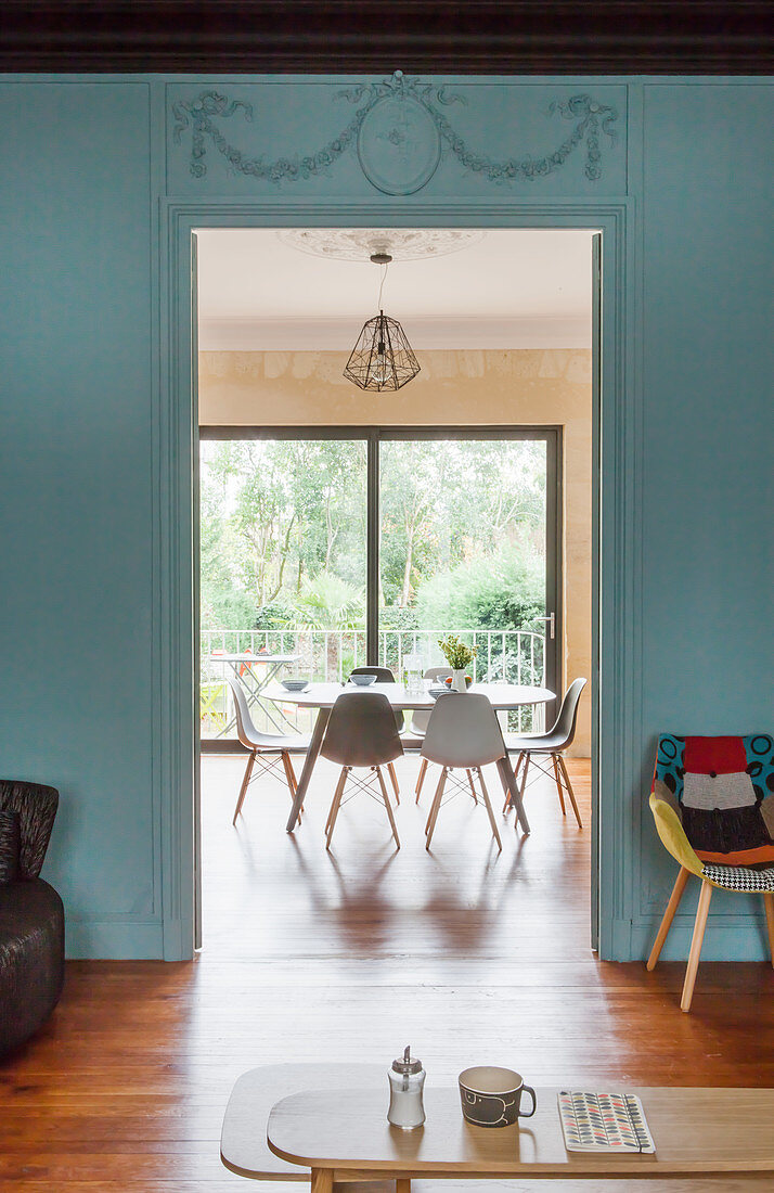 Blick von Wohnzimmer mit blau-grauer Wand in das Esszimmer mit Tisch und Stühlen