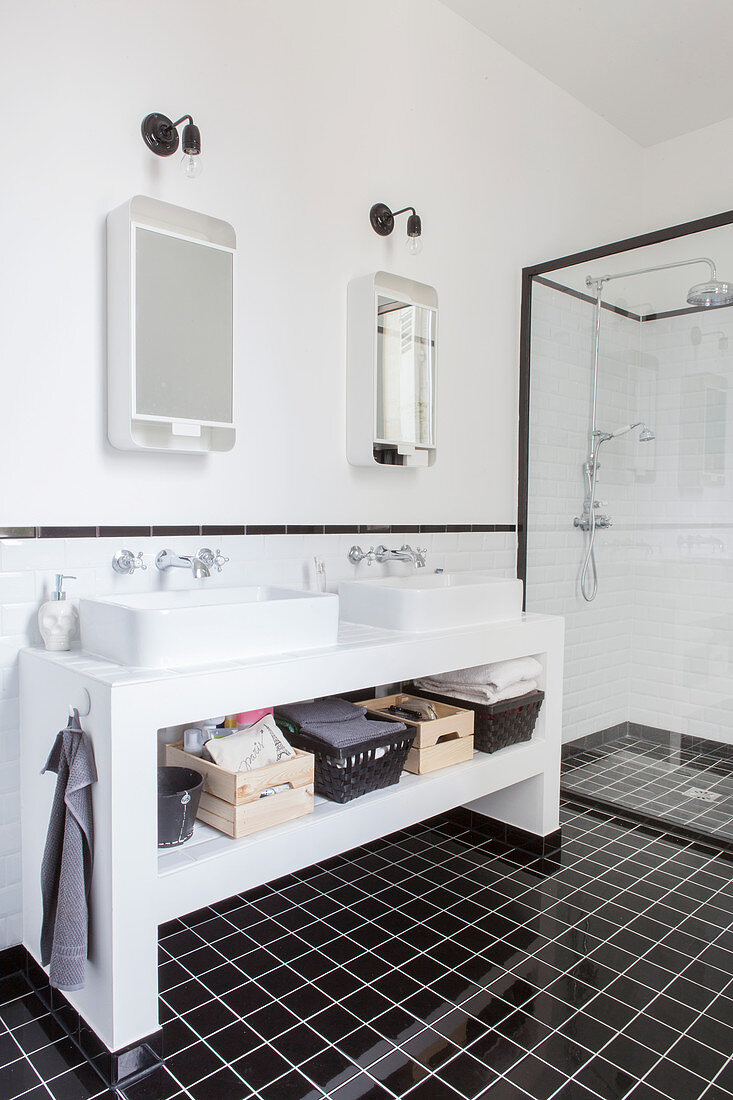 Twin sinks on washstand and shower cubicle in black and white bathroom