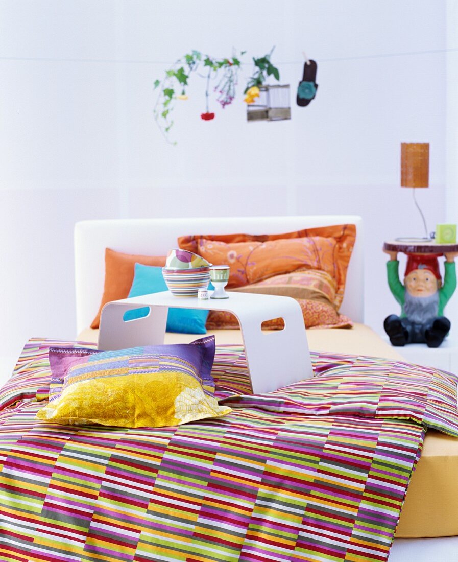 Bunte Textilien im Schlafzimmer mit Zwerg als Nachttisch