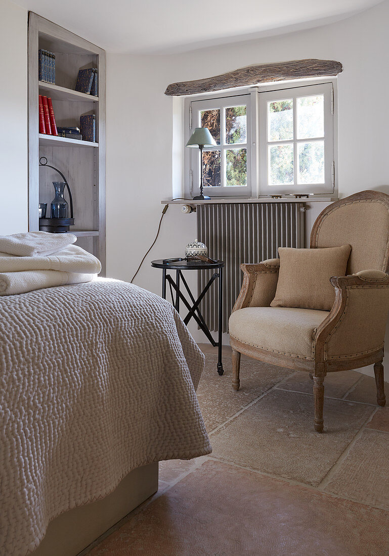 Antiker Sessel mit Kissen, Beistelltisch und Einbauregal in ländlichem Schlafzimmer