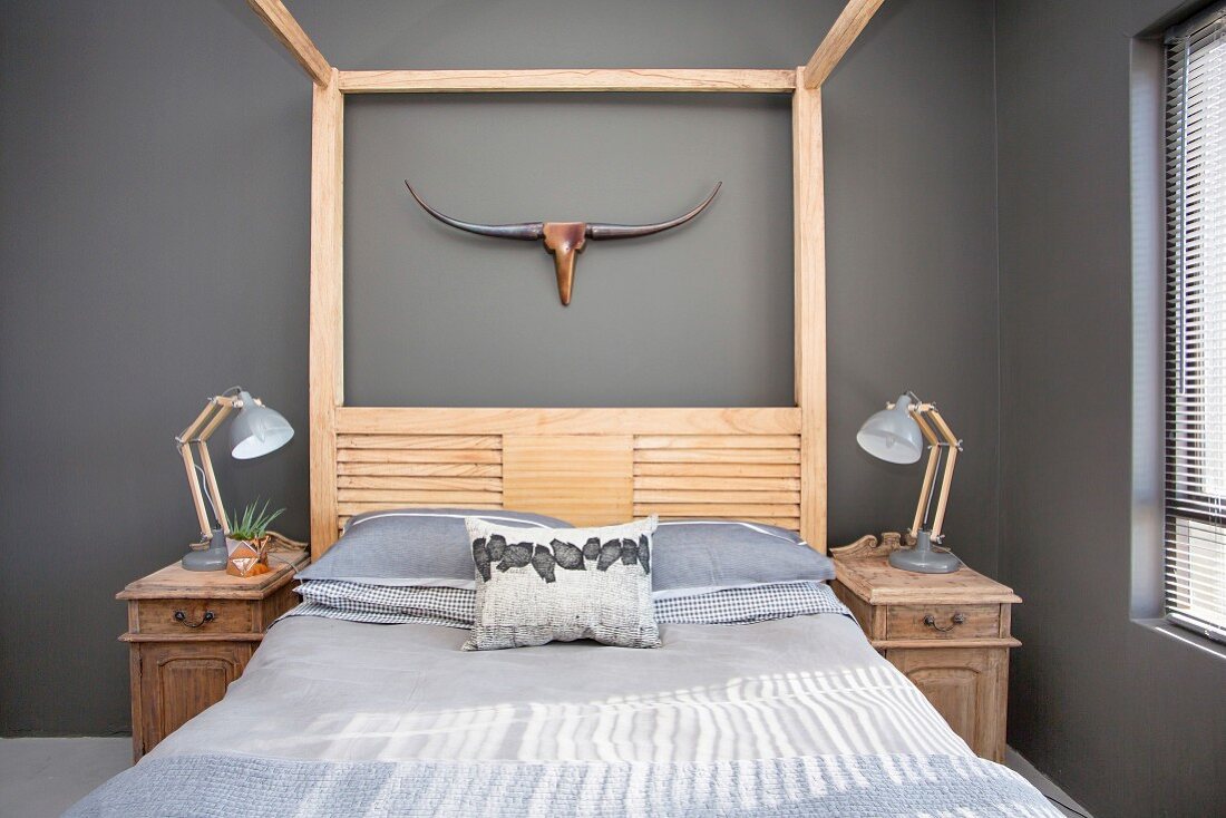 Doppelbett mit Holzgestell und Nachtkästchen vor grauer Wand