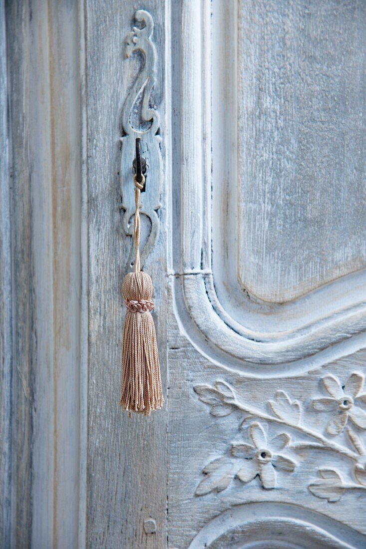 Key with tassel in artistically carved, antique wooden door