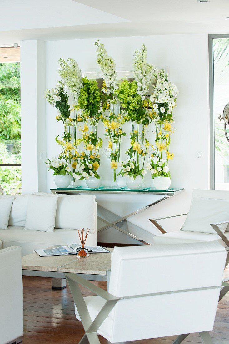 weiße Designer-Ledermöbel in Loungebereich mit üppiger Blumendekoration