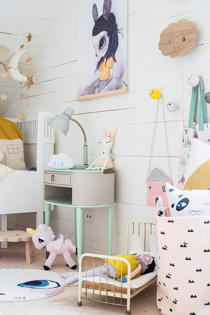 Vintage bedside table, cot and animal motifs in child's attic bedroom