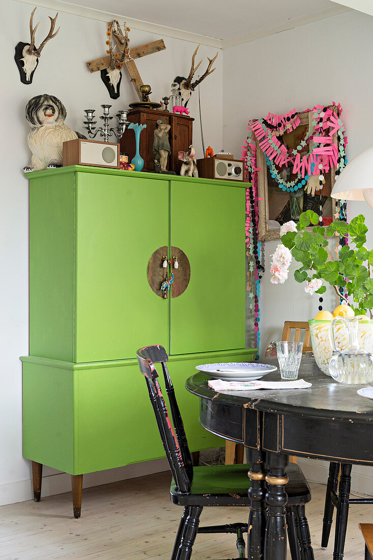 Black dining set in front of green cabinet and kitsch decorations