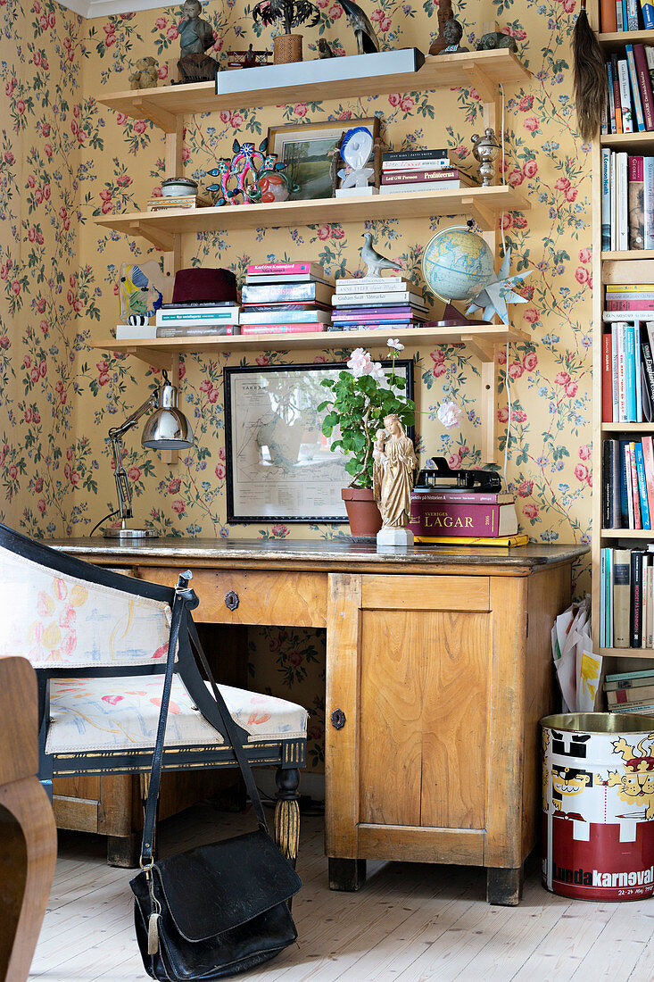 Desk and shelves against wall with floral wallpaper