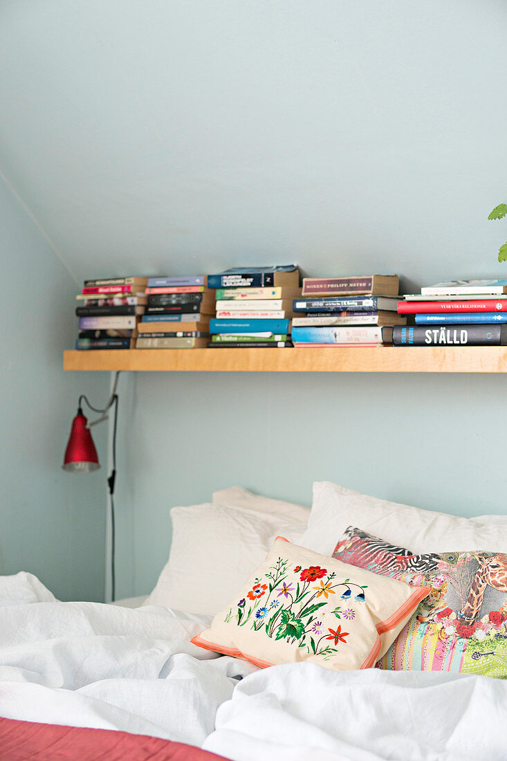 Regalbrett mit Büchern über dem Bett unter der Schräge