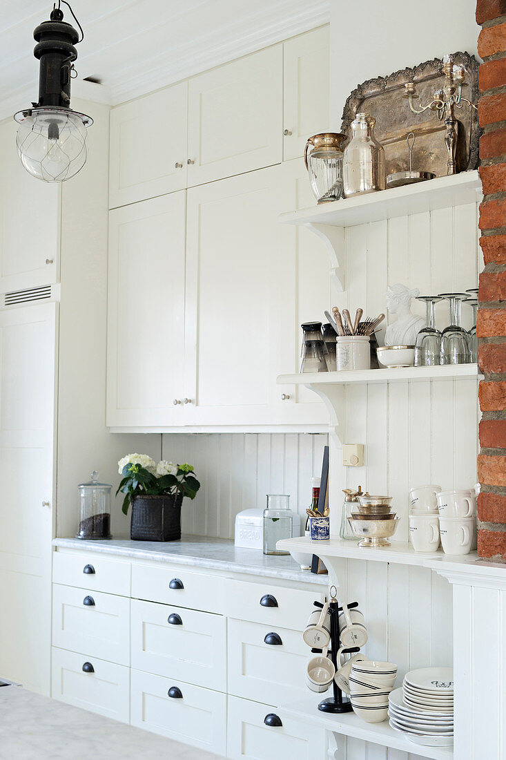 Ample storage and vintage ornaments in bright country-house kitchen