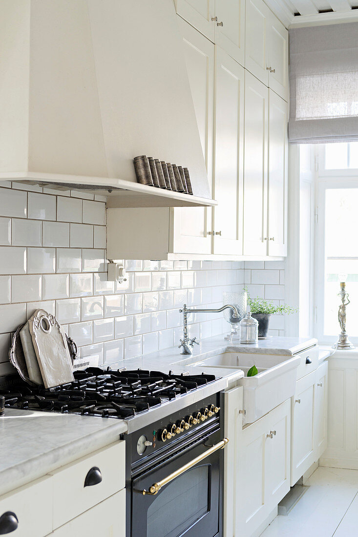 Vintage-style gas cooker in bright country-house kitchen with white cupboards