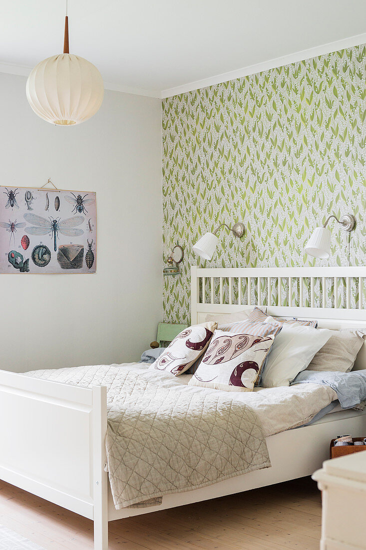 White bed against green-patterned wall in vintage-style bedroom