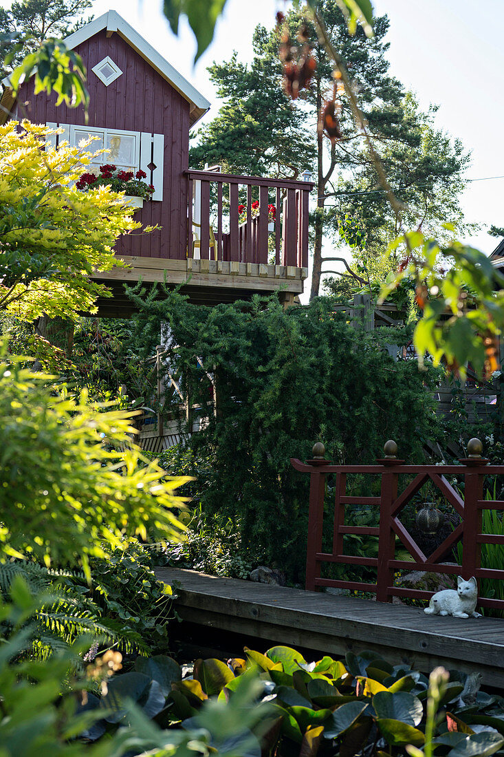 Blick auf Holzbrücke mit Katze, oberhalb skandinavisches Gartenhäuschen