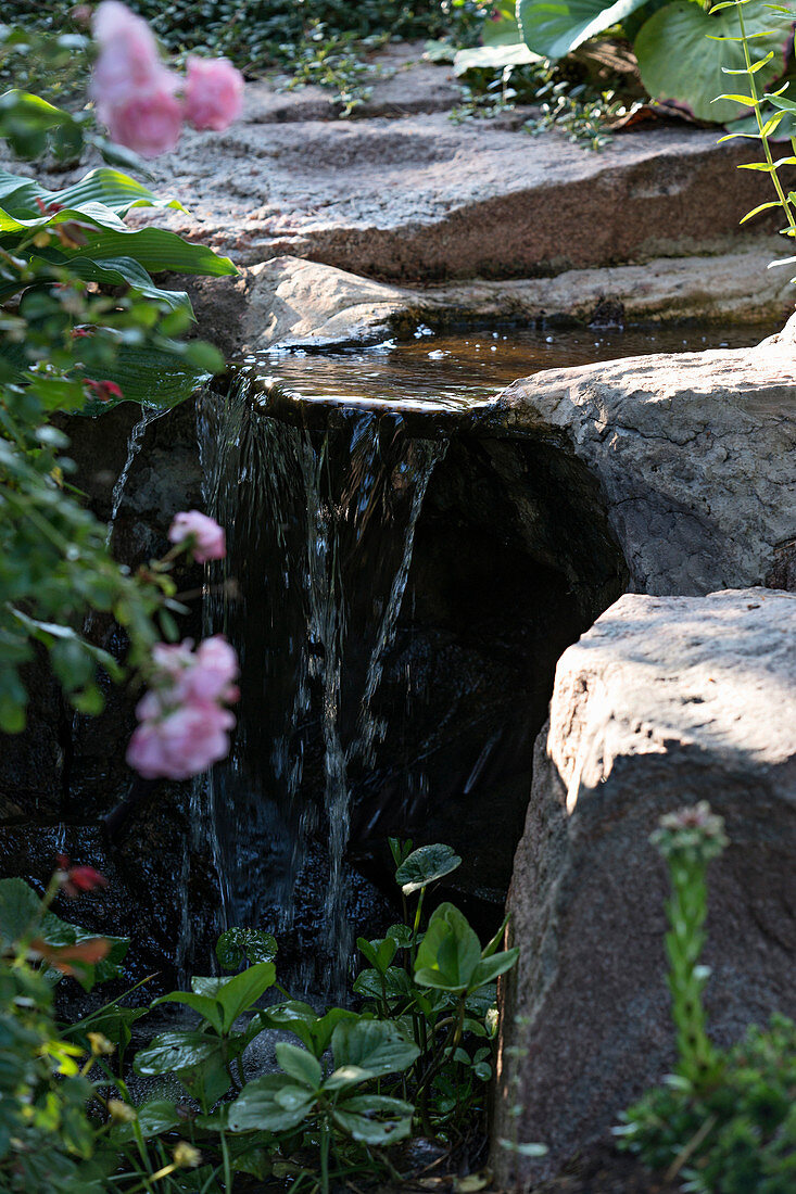 Wasser plätschert von Steinblöcken im Garten