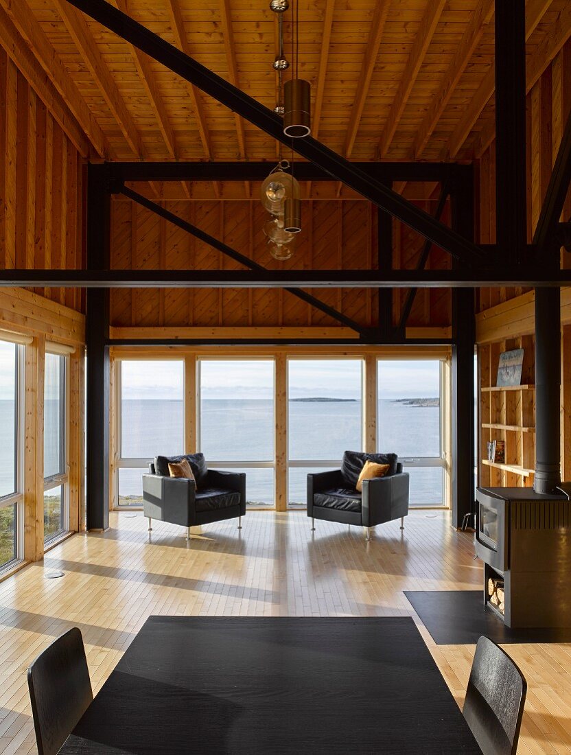Modern wooden house with glass wall, black girders and black furniture