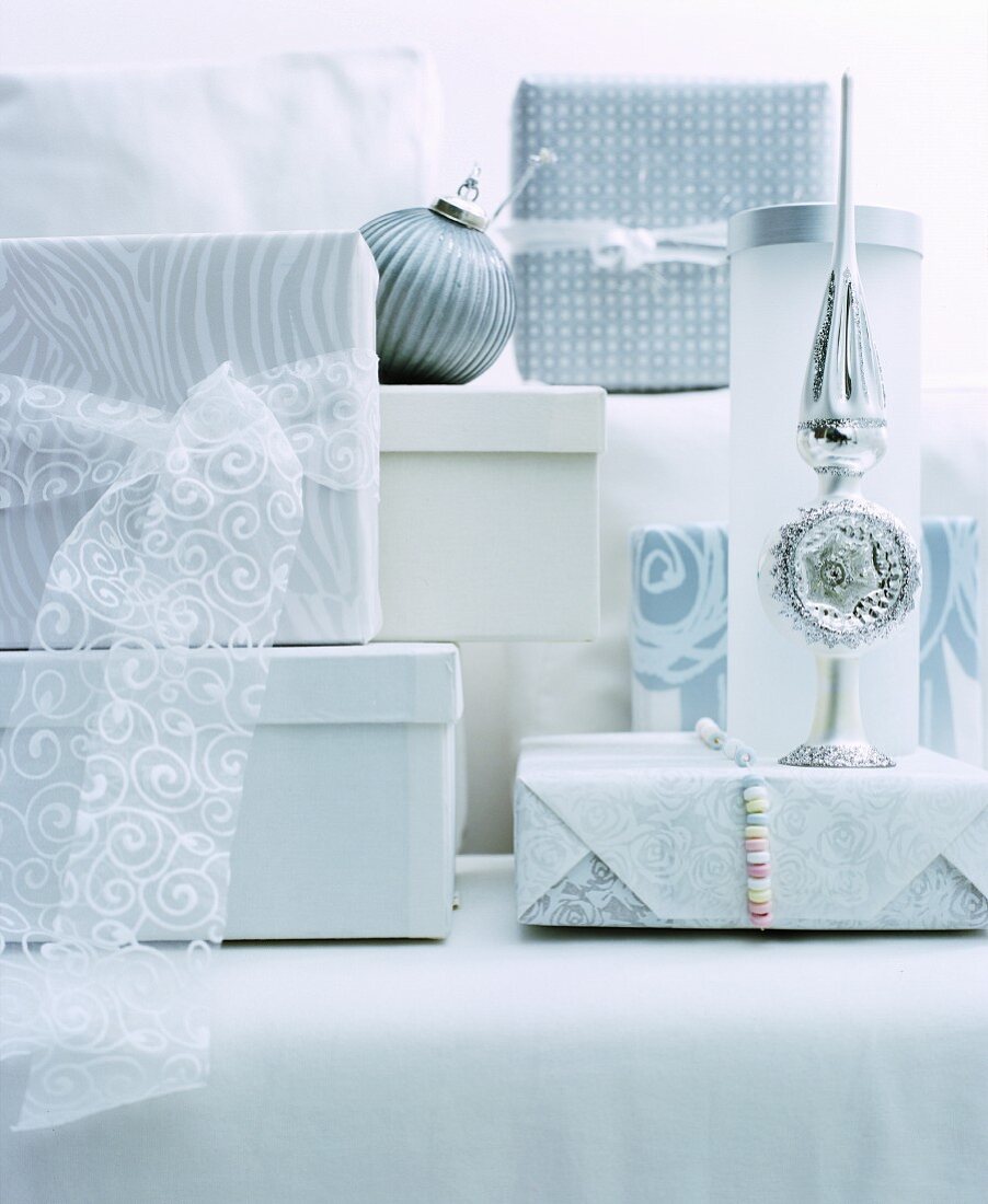 Verpackte Geschenke und Christbaumschmuck in Weiß und Silber