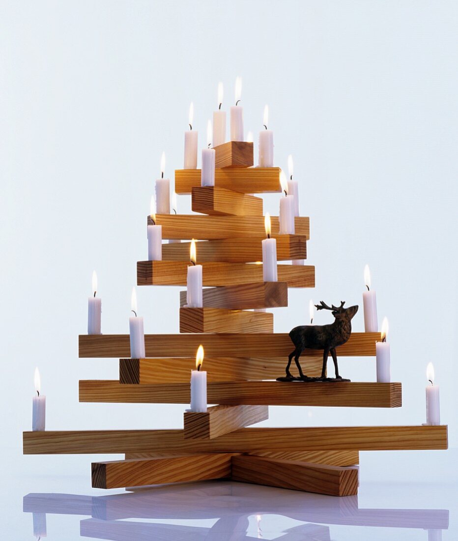 Lit candles and stag figurine on wooden Christmas tree