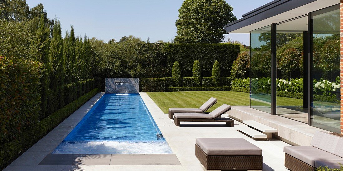 Pool and sun loungers on terrace next to glass façade