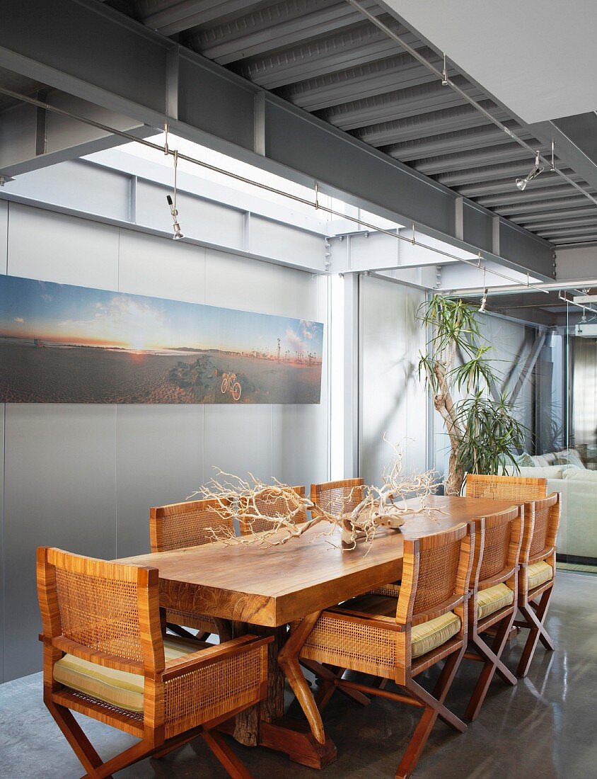 Wooden table, wicker chairs and steel structure in dining area