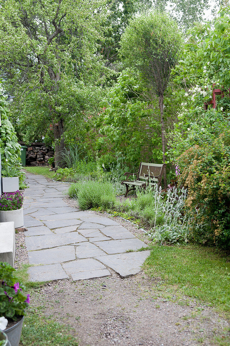 Weg mit großen Steinplatten im üppigen Garten