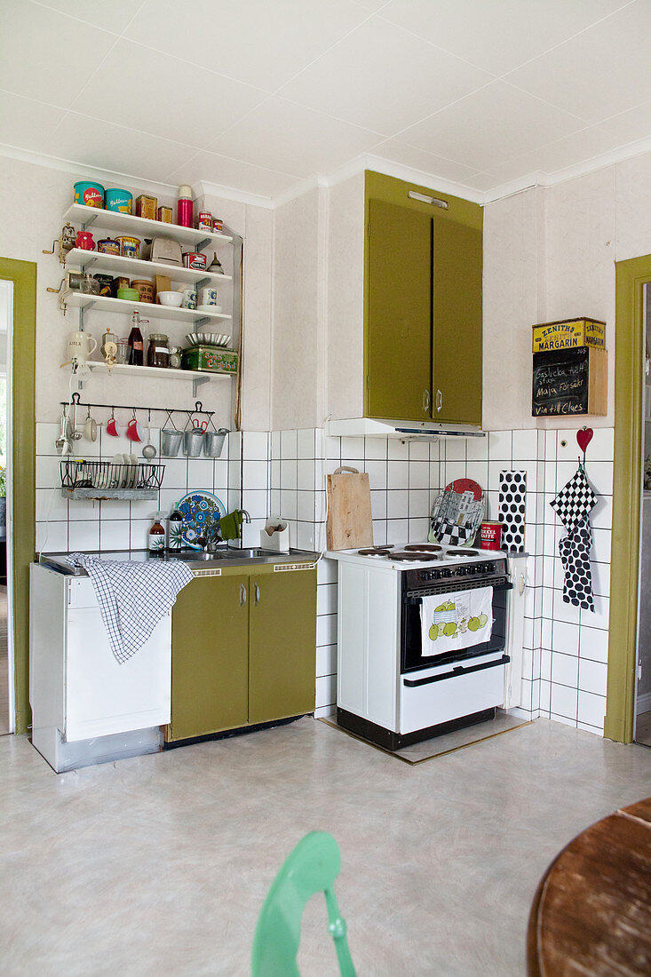 Retro-Küche mit olivgrünen Fronten, altem Herd und Wandregalen