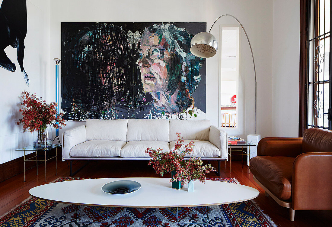 Klassiker, ovaler Couchtisch, Couches, Bogenlampe und großformatiges Gemälde im Wohnzimmer