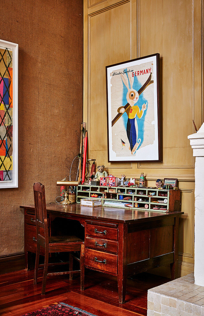 Aniker Schreibtisch und Stuhl an der Wand mit Kassettenvertäfelung und Plakat