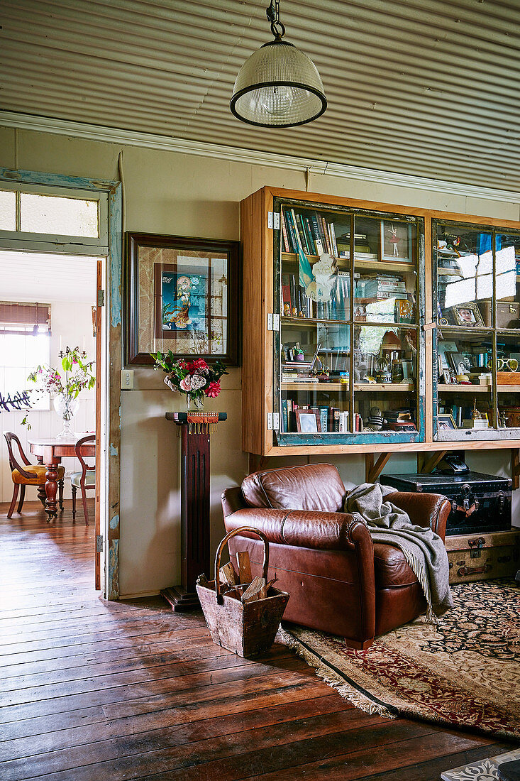 Display cabinet on the wall and vintage leather armchairs in a converted stable