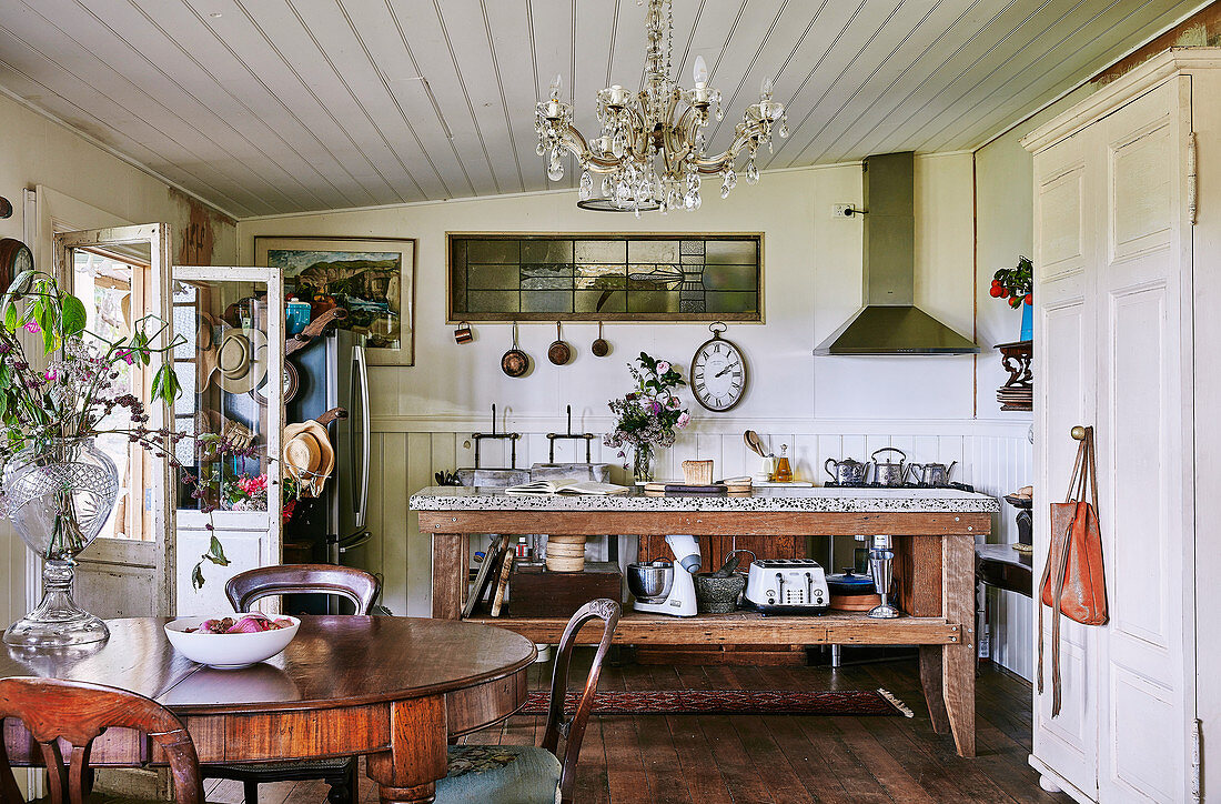 Runder Esstisch mit Stühlen und rustikaler Holztisch mit Granitplatte in der Küche in umgebautem Stall