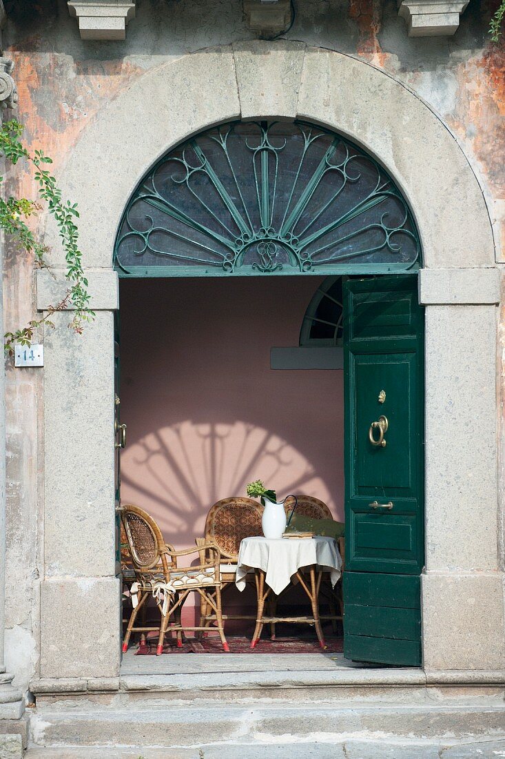 Traditioneller Rundbogen-Eingang mit geöffneter, dunkelgrüner Flügeltür