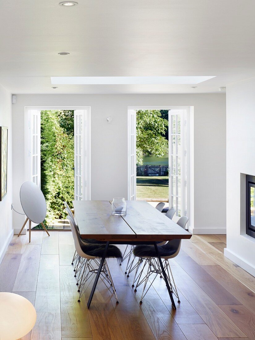 Classic chairs in elegant dining area with exotic-wood parquet floor and view of summery garden