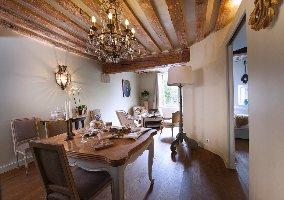 Chandelier and rustic wood-beamed ceiling in dining area with historical ambiance