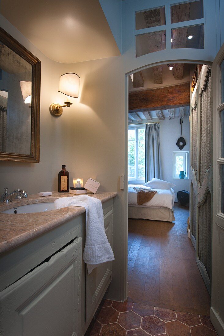 Blick von beleuchtetem Badezimmer in Schlafzimmer mit traditionellem Flair