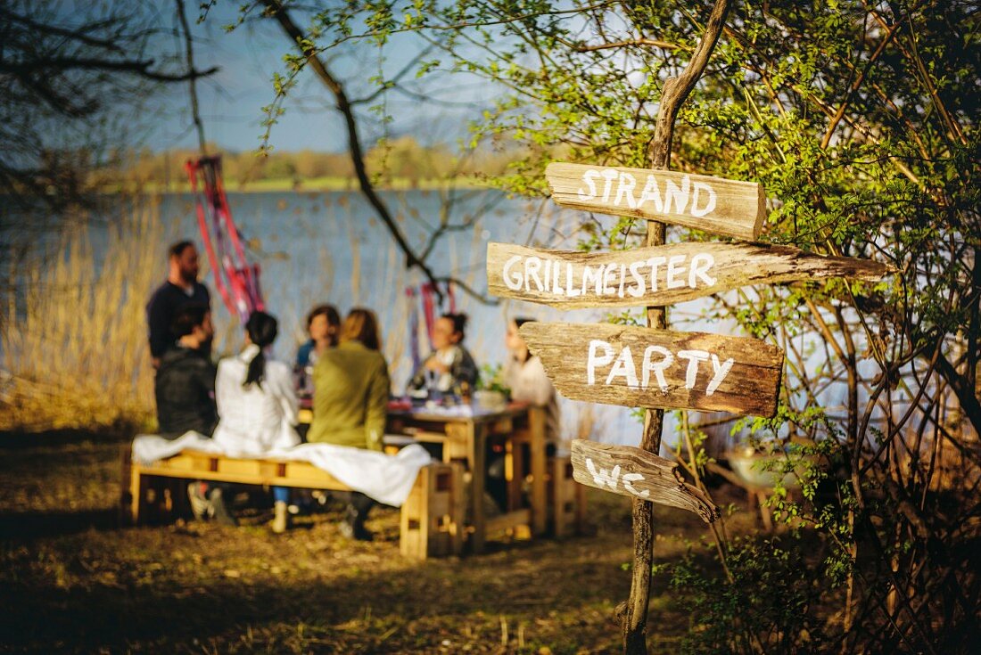 Rustic hand-made signpost with lettering on wooden boards for summer party