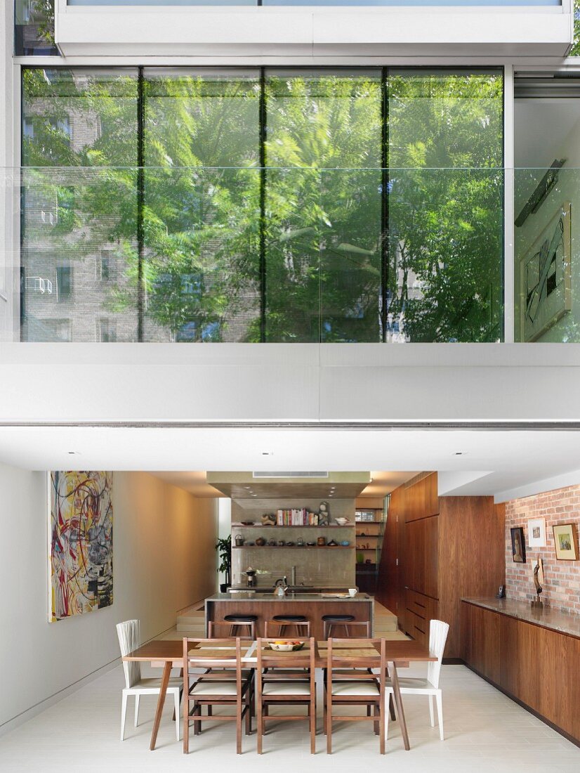 View of ground-floor dining area and trees reflected in glass façade of first floor