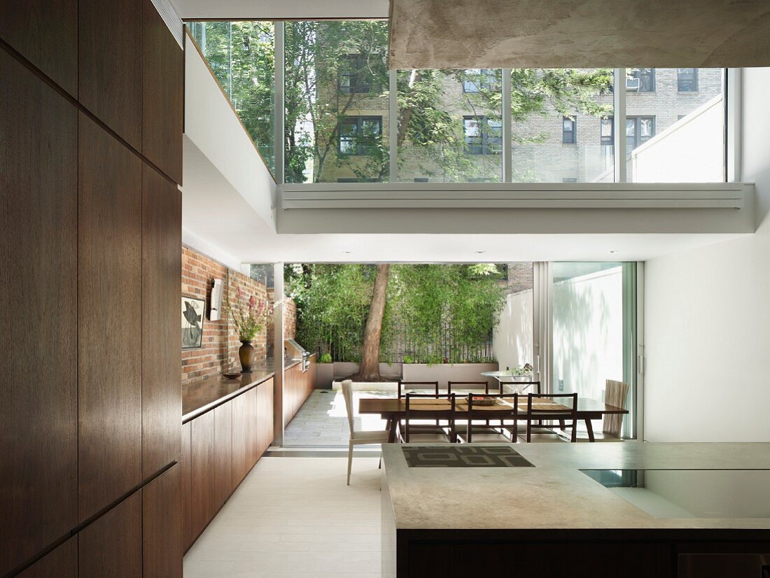 Blick von Küchenbereich auf Essplatz und Terrasse, durchgehendes Sideboard mit Außenküche