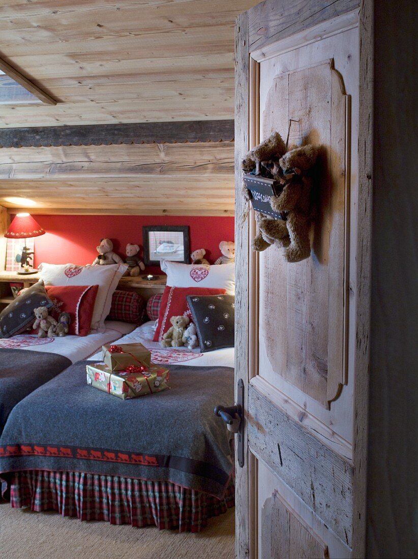 Einblick in gemütliches, beleuchtetes Chalet-Schlafzimmer mit Teddybären und Weihnachtsgeschenken