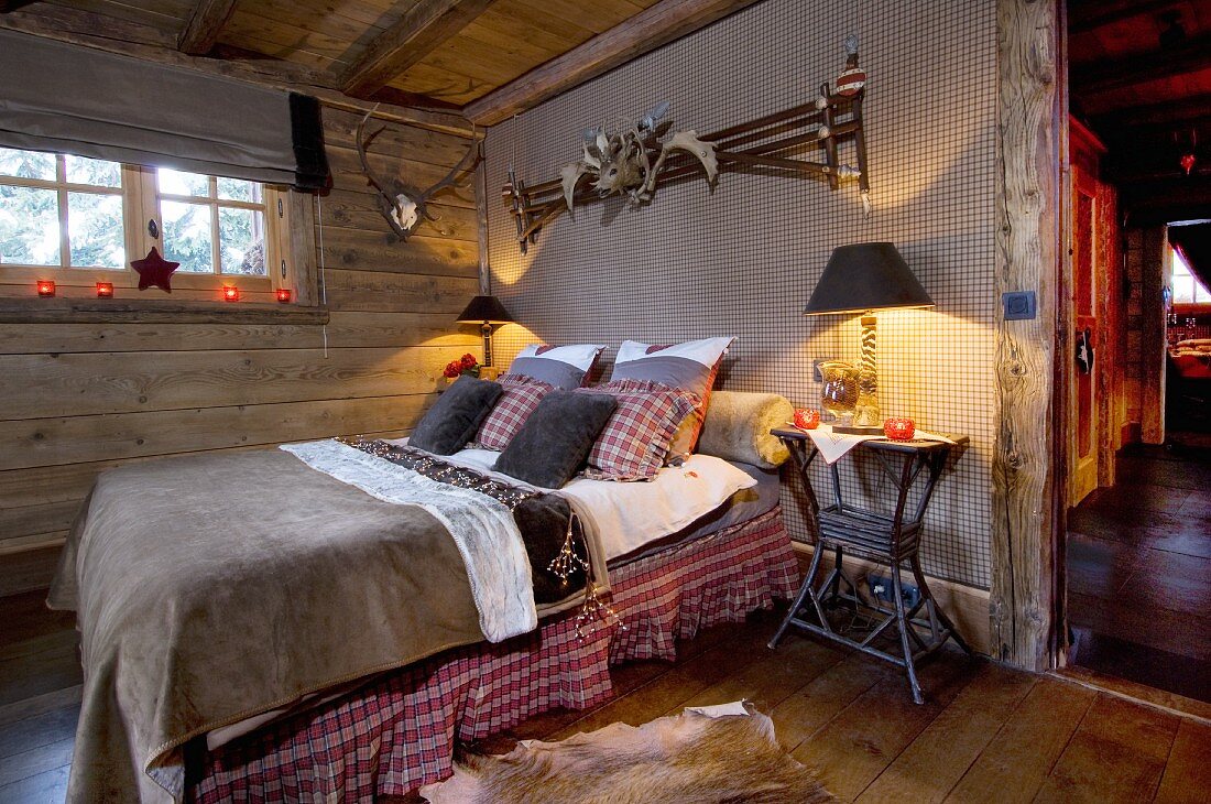 Schlafzimmer im rustikalen Landhausstil mit Tiertrophäen und weihnachtlichem Kerzenlicht