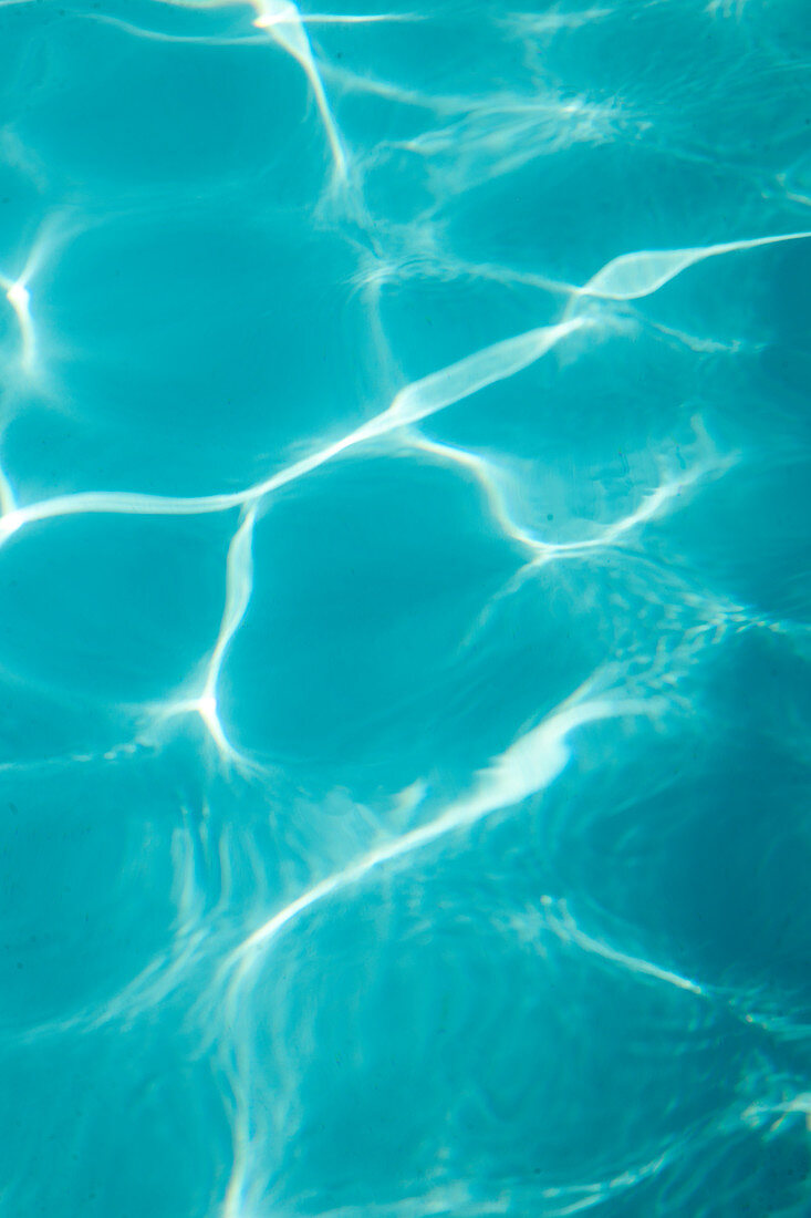 Reflections of sunlight on blue water in swimming pool