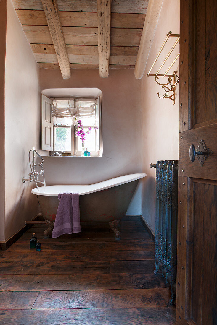 Free-standing bathtub below window in vintage-style bathroom
