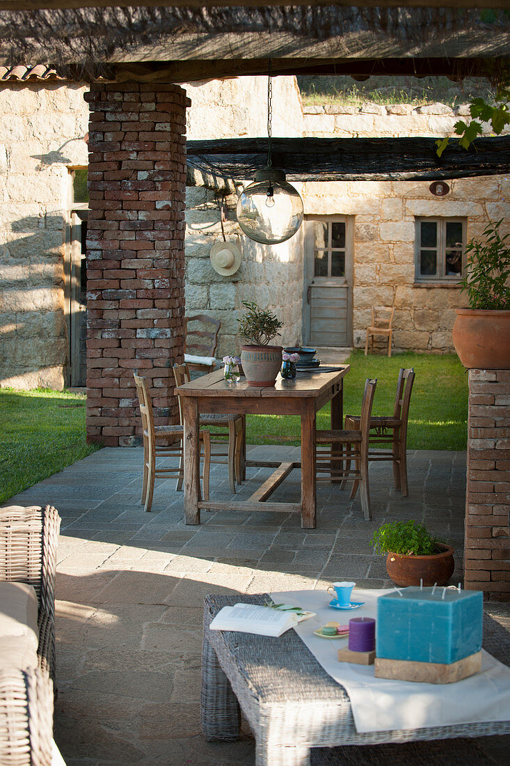 Holztisch auf überdachter Terrasse im mediterranen Garten