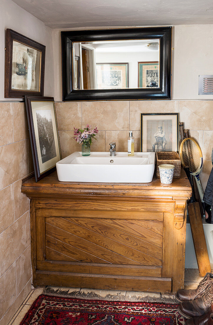 Countertop sink on old wooden washstand in bathroom with low ceiling