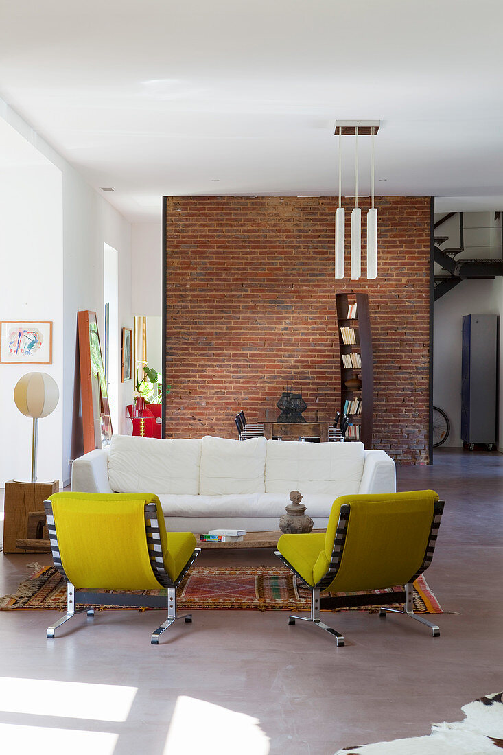 Yellow easy chairs and white sofa in open-plan loft interior