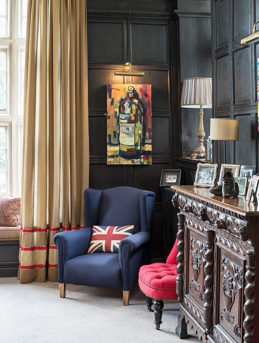 Union-flag cushion on blue armchair in living room with panelled walls