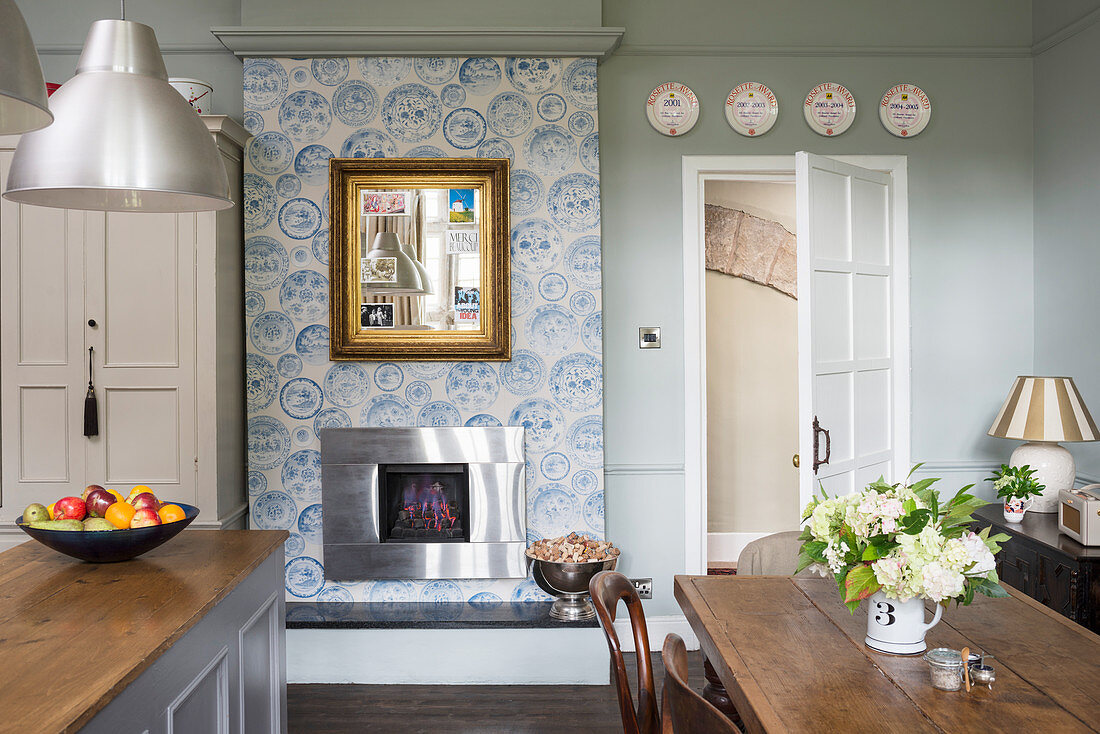 English-style kitchen-dining room with open fireplace and patterned wallpaper on chimneybreast