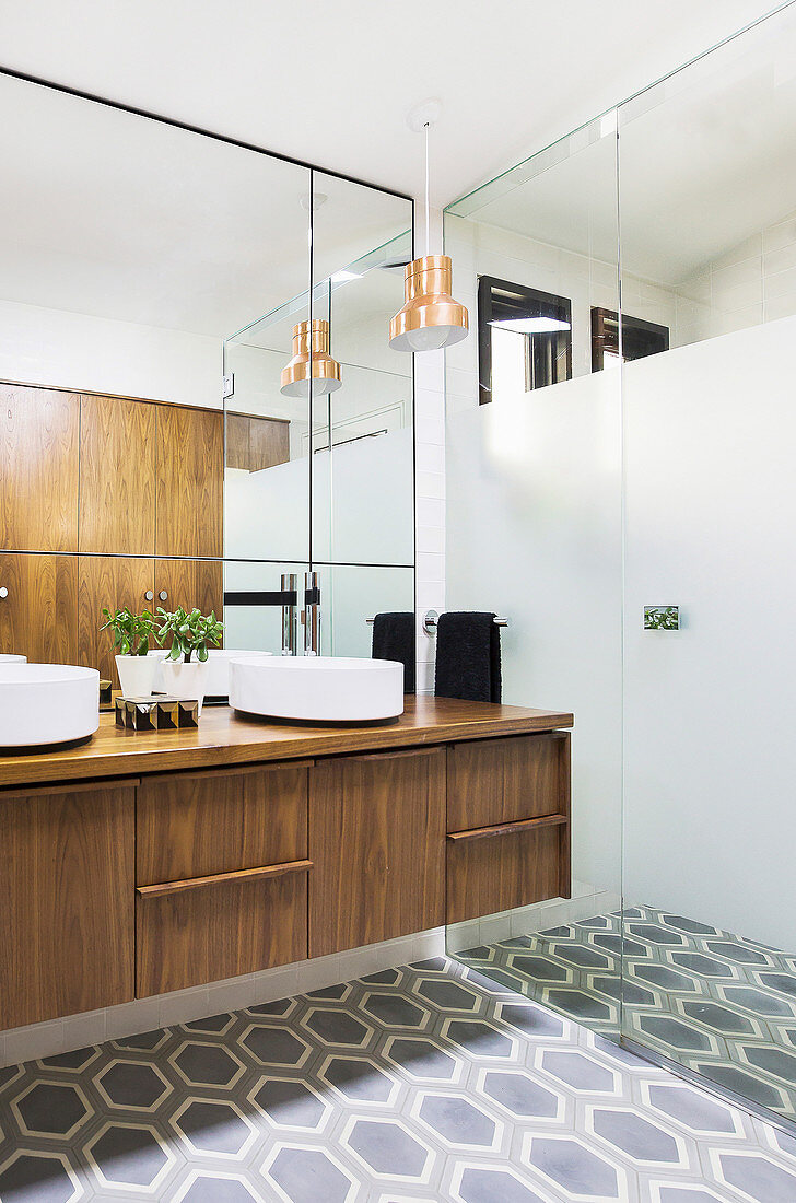 Elegantes Badezimmer mit begehbarer Dusche, Doppelwaschtisch aus Walnußholz, Wandspiegel und sechseckigen Bodenfliesen