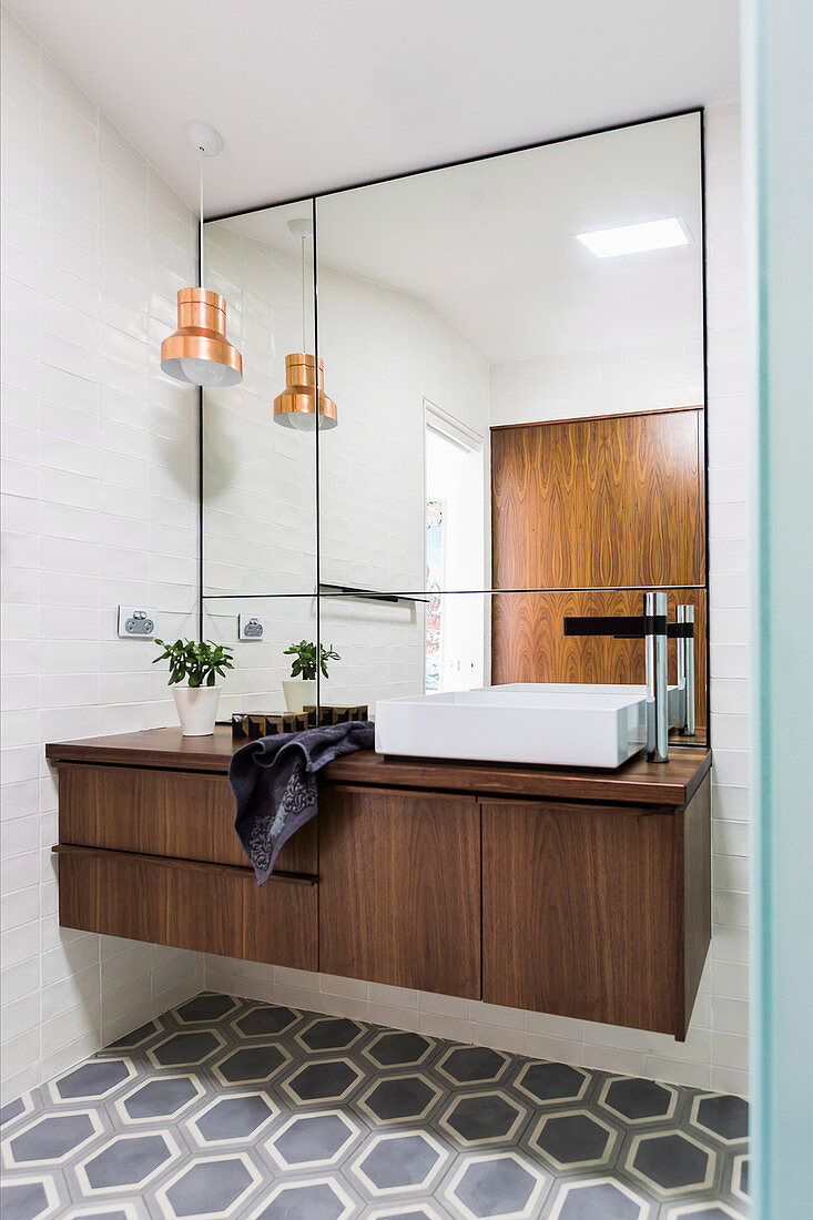 Elegantes Badezimmer mit Waschtisch aus Walnußholz, Wandspiegel und sechseckigen Bodenfliesen