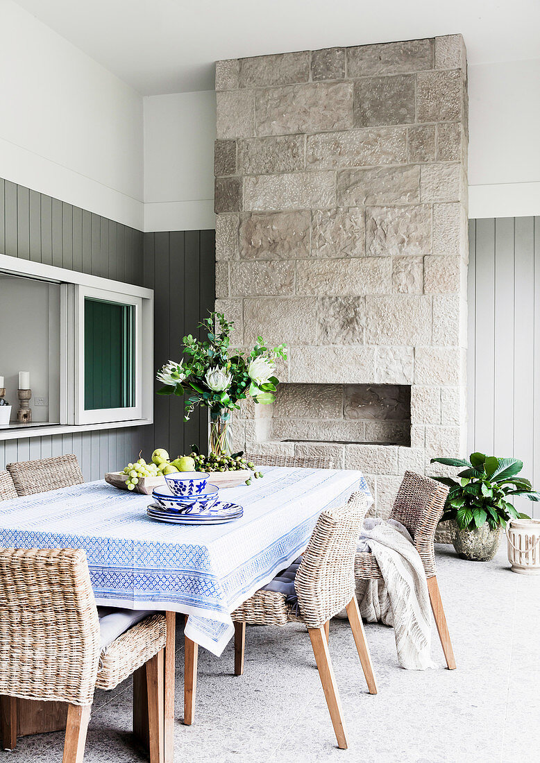 Esstisch mit Stühlen und Kamin auf überdachter Terrasse