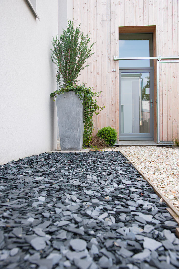 Bed of slate and gravel path in front garden leading to glass front door