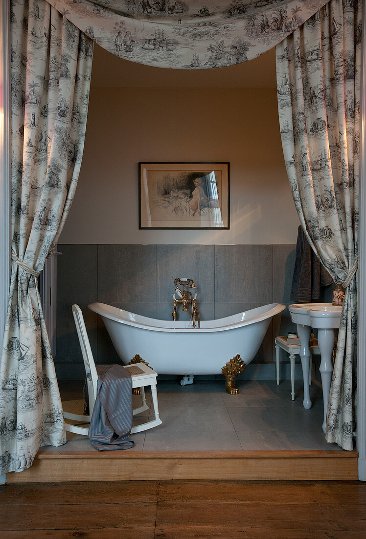 Free-standing bathtub in bathroom partitioned by curtains