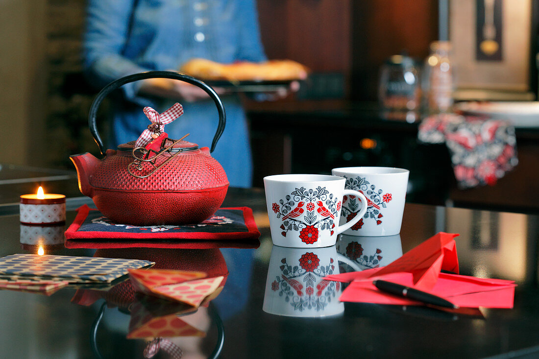 Bird-patterned mugs next to red cast-iron teapot