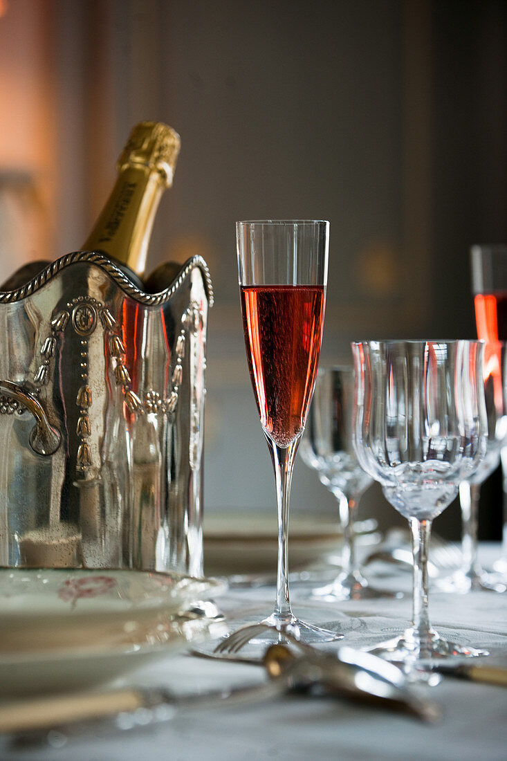 Roter Champagner im Glas vor silbernem Flaschenkühler